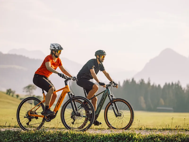 Pärchen auf E-Bikes bei Sonnenuntergang in den Alpen